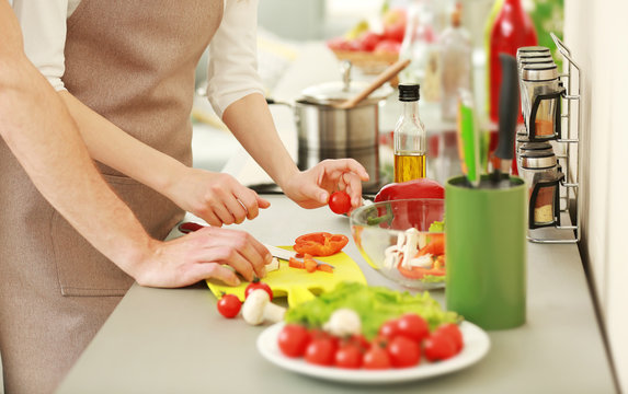 Loving couple cooking salad in kitchen