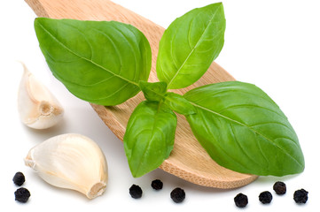 Kochlöffel mit Basilikumblatt, Knoblauch und Pfefferkörnern