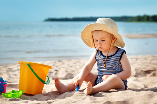 baby boy sitting on the beach in summer day