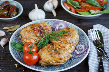 Roasted chicken and vegetables on dark wooden background