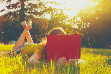 girl reading book in warm summer grass