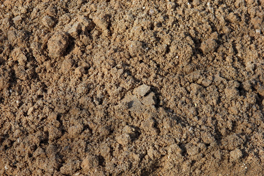 raw wet quarry coarse brown sand foreground closeup