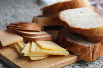 sliced fresh bread and sliced different varieties of cheese on w