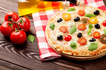 Italian pizza with cheese, tomatoes, olives and basil
