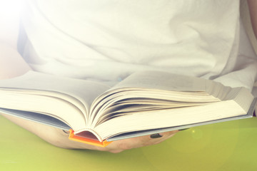 Young girl reading an  open book  old book. Books and reading are essential for self improvement, gaining knowledge and success in our careers, business and personal lives.