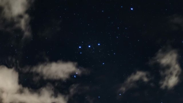 time lapse in 4k of the stars of constellation Orion moving in the background of night clouds illuminated by city lights