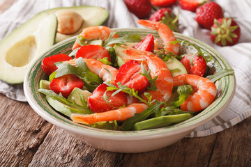 Fresh salad with strawberries, avocado, shrimp and arugula close-up. horizontal
