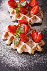 waffles with fresh strawberries and mint close-up on the slate. vertical
