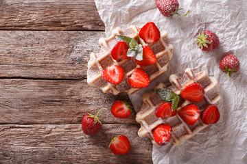 Belgian waffles with strawberries and powdered sugar closeup. Horizontal top view
