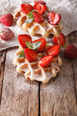 rustic waffles with strawberries, powdered sugar and mint closeup. vertical
