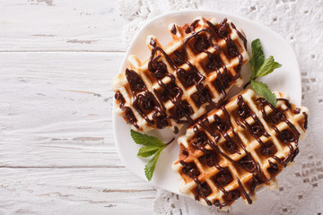 Dessert waffles with chocolate topping on a plate. Horizontal top view
