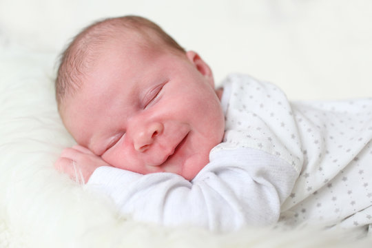 3-weeks newborn girl smiles during a sleep