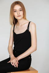Naklejka premium Young European woman posing in studio for test photo shoot showing different poses sitting on bar stool