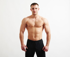 Obraz premium Bare-chested young athletic man over white background
