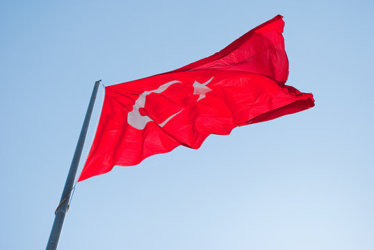 Red waving flag of Turkey in blue sky