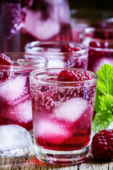 Fototapeta na wymiar Sweet cocktail with raspberries, ice and soda, vintage wooden ba