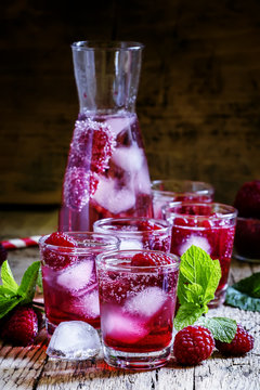Sweet cocktail with raspberries, ice and soda, vintage wooden ba