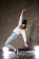 Young woman in black hat dancing on tiptoe