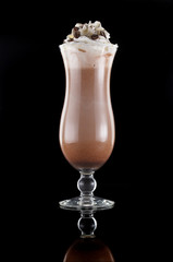 Glass of chocolate milkshake with whipped cream over black background