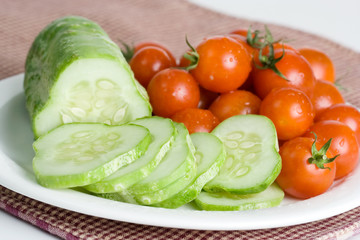 Fresh Cucumbers and Cherry Tomatoes – A plate of sliced cucumber and whole cherry tomatoes.