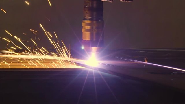 Lights of sparks on the plasma cutter while cutting a big metal sheet in the factory