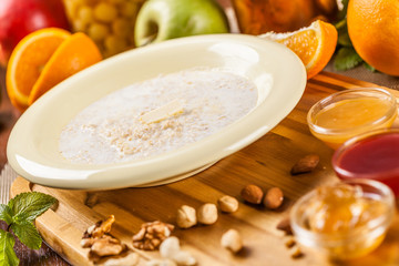 Oatmeal porridge with nuts, jam and fruits on wooden board