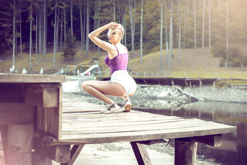 Young woman posing on pier wearing white shorts.