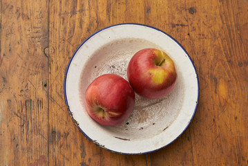 apples on rustic plate on wooden table   