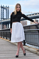 Obraz premium Attractive blond fashion model posing pretty on the pier with Manhattan Bridge on the background, New York City.