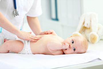 Obraz na płótnie Canvas Doctor pediatrician examines baby tummy