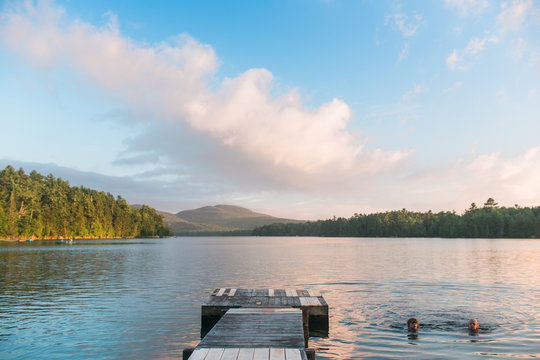 Two boys swimming in lake beside jetty
