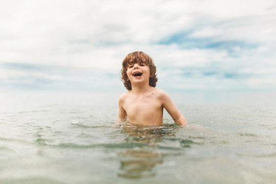 Young boy standing in sea, laughing