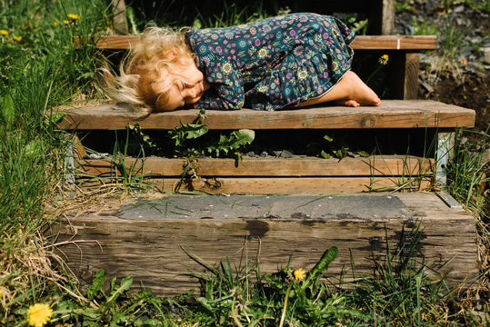 Girl sleeping on wooden step in sun