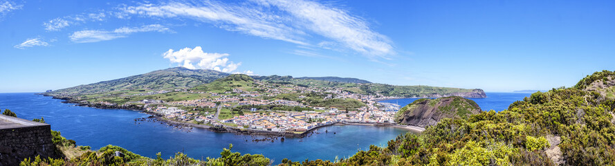 Fototapeta na wymiar View of the town of with the bay on the background of green hills and blue sky, to the Azores