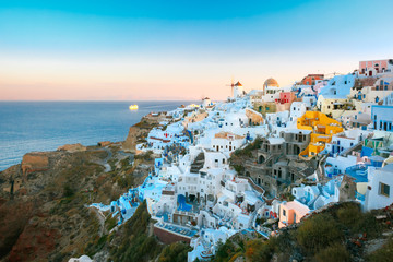 Picturesque famous view, Old Town of Oia or Ia on the island Santorini, white houses and windmills at sunset, Greece