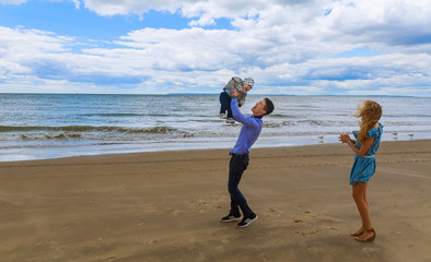 Dad and mom playing with young son on the beach
