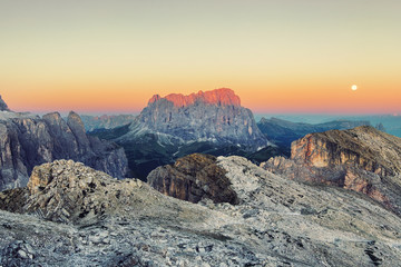 The sun in orange sky over rocky mountains