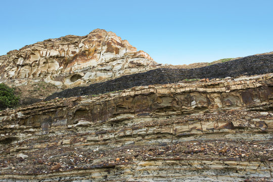 Dark coal seam in sedimentary layers in cliff. Newcastle, New South Wales, Australia. 