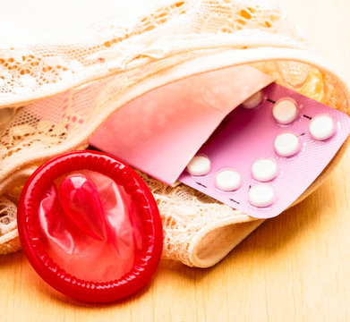 Oral contraceptive pills and condom on lace lingerie