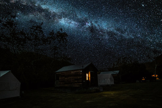 Log cabin and tent under starry sky