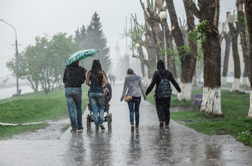 Group of people walking down the street at heavy rain in motion blur. Concept bad weather,...