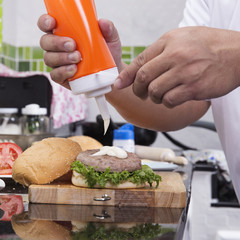 Chef putting mayonnaise on the Hamburger bun