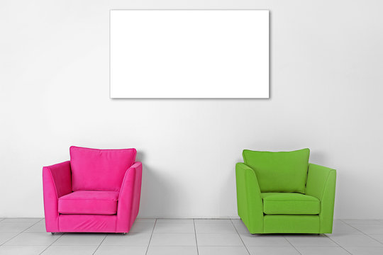 Living room interior with armchairs and picture frame on white wall background