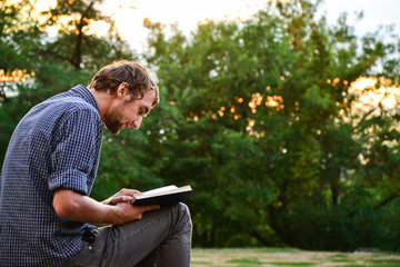 Guy reading book in park