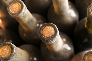 Stacks of dusty wine bottles on wooden background, upside view. Close up