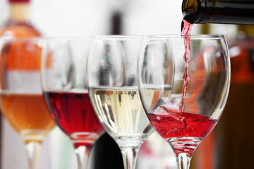 Red wine pouring into glasses, closeup