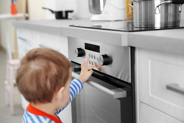 Little child playing with electric stove in the kitchen