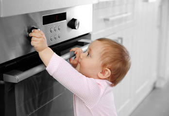 Little child playing with electric stove in the kitchen