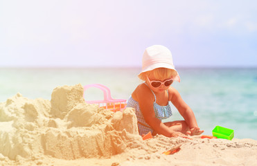 cute little girl play with sand on beach