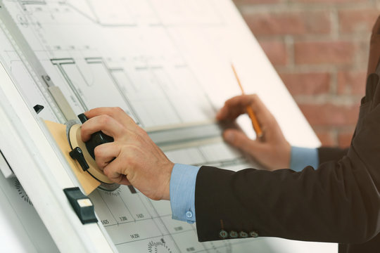 Engineer working with blueprint on panel board indoors